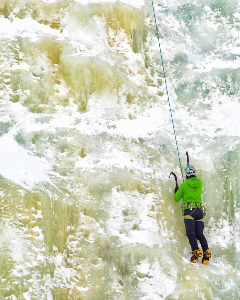 One man wearing blue jacket climbing ice wall